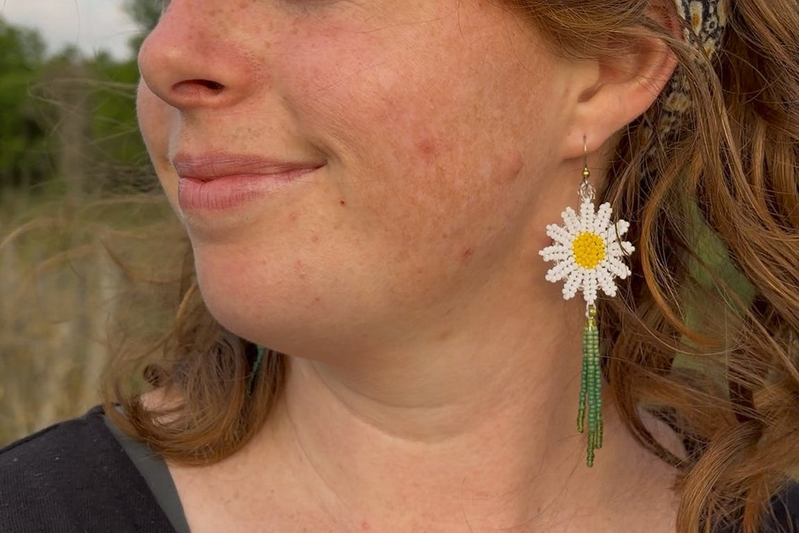 Woman wearing a floral headband and daisy earrings outdoors